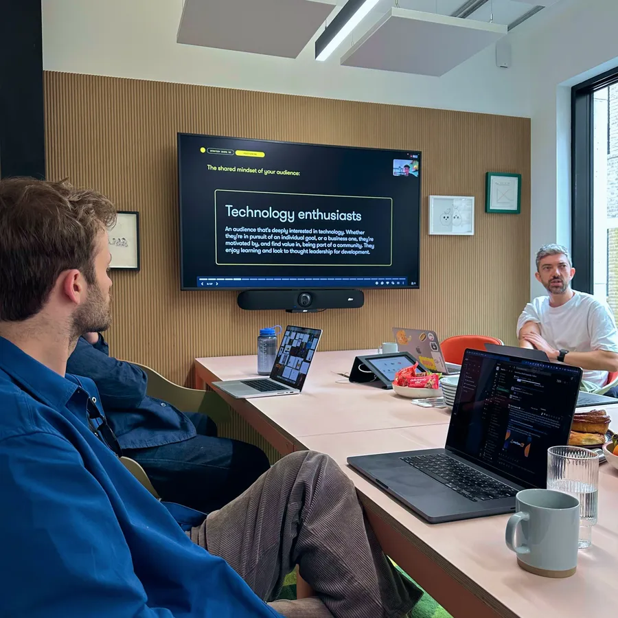 Jake and the Koto team in a meeting room, a slide reading “Technology enthusiasts” on the screen behind them