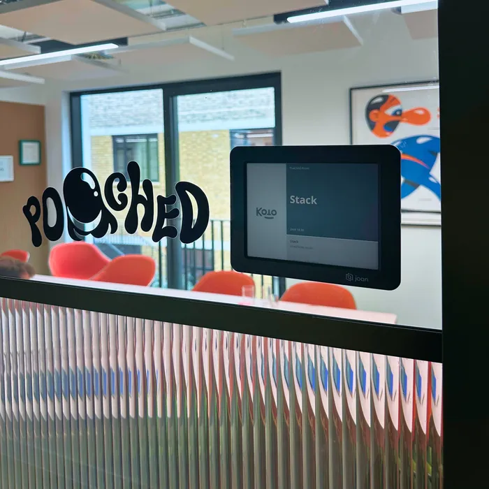 A room sign reading “Poached” next to a booking panel showing the room reserved for Stack Overflow, at Koto’s London studio