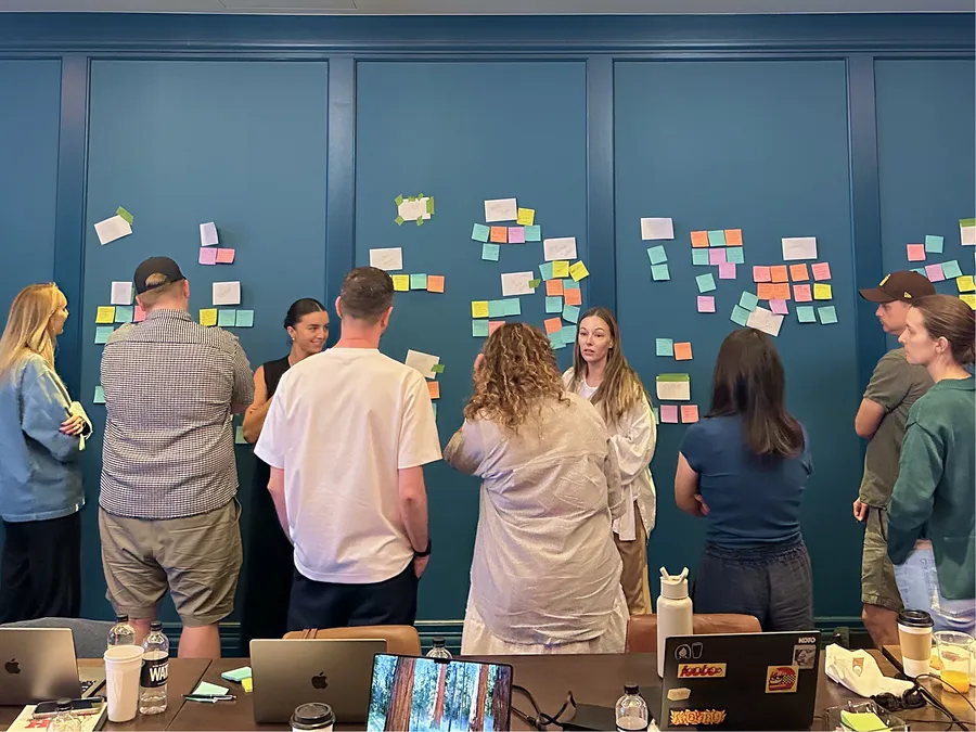 The Koto and Stack Overflow teams grouped around a wall of sticky notes from the Nashville workshop